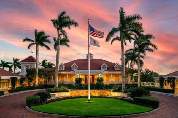 Aerial photorealistic view of the Collier's Reserve Mediterranean clubhouse surrounded by lush conservation land, golf course, and the Gordon River at sunset, dramatic cinematic lighting, 8K ultra sharp real estate photography