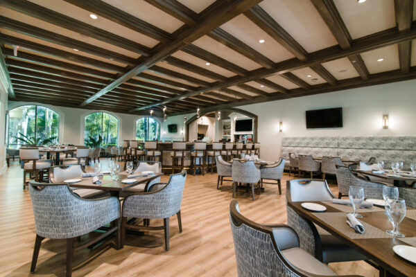 Photorealistic 8K image showcasing the elegant interior of the Cypress Woods Grille Room with members enjoying fine dining, warm ambient lighting, dark wood accents, white table linens, and large windows overlooking the golf course at dusk, sophisticated upscale restaurant atmosphere