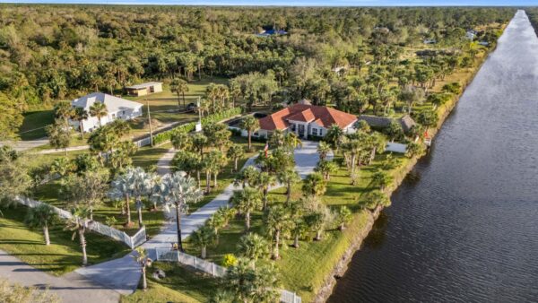 Alternative angle product shot of the guide standing upright beside a scale model of a luxury Florida estate home with swimming pool, clean studio setting with soft gradient background, dramatic side lighting, 8K ultra-detailed