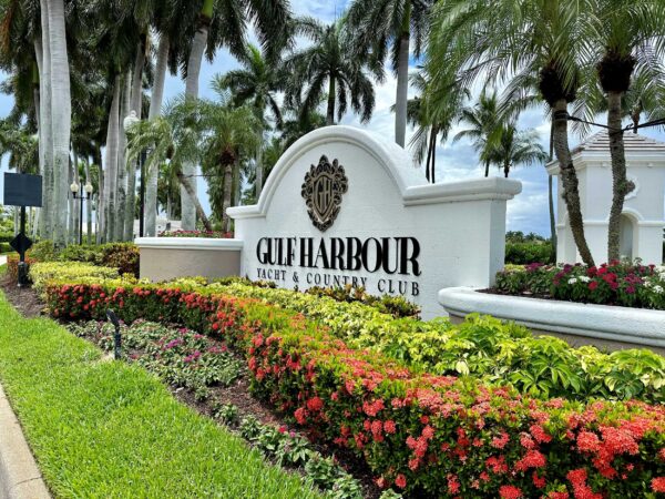 Photorealistic 8K studio product hero shot of Gulf Harbour Yacht & Country Club entrance sign with manicured landscaping, luxury cars visible, golden hour lighting, clean centered composition on a premium dark gradient background, ultra sharp detail, cinematic color grading