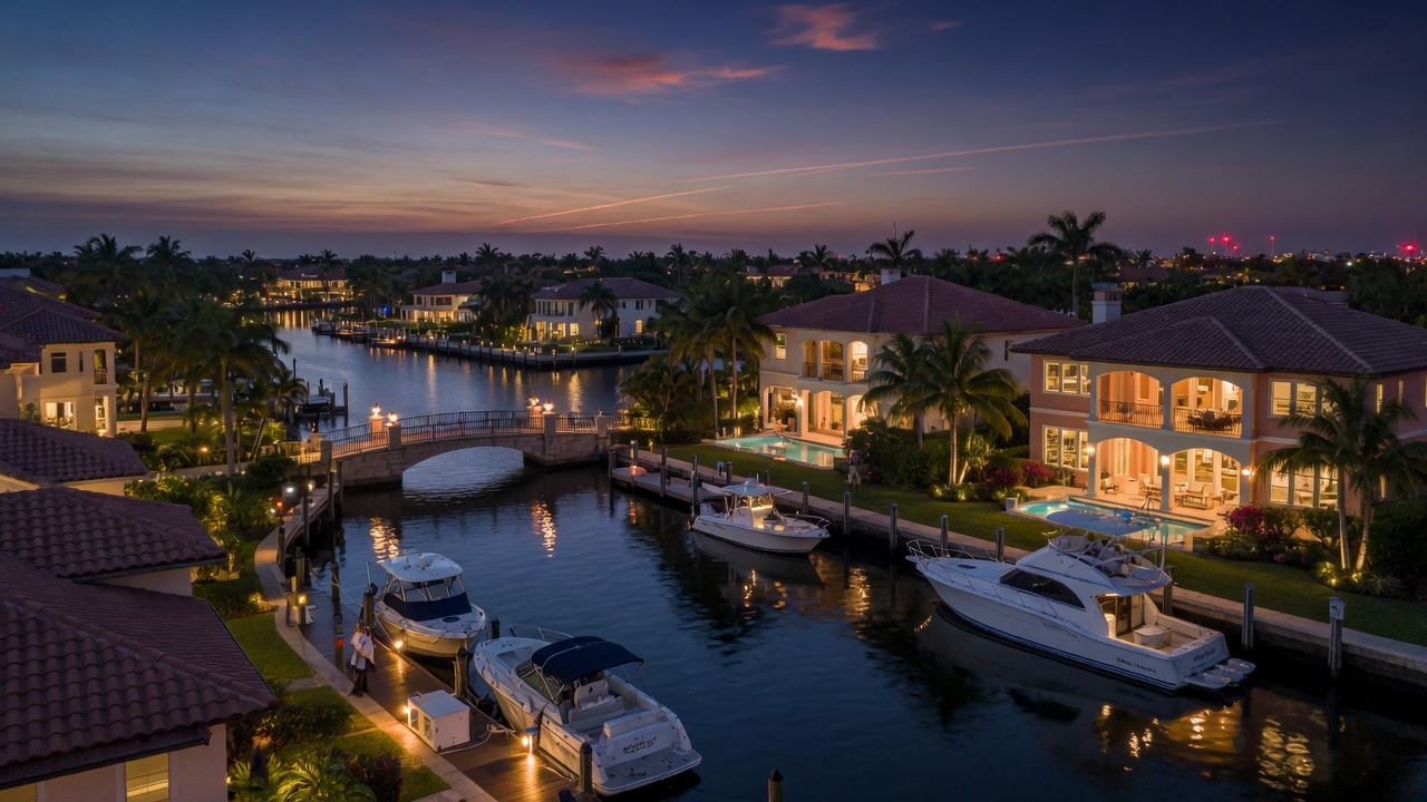 Ultra-realistic 8K dusk photograph of a luxury Naples waterfront community with illuminated homes, canals, and boats docked along private piers