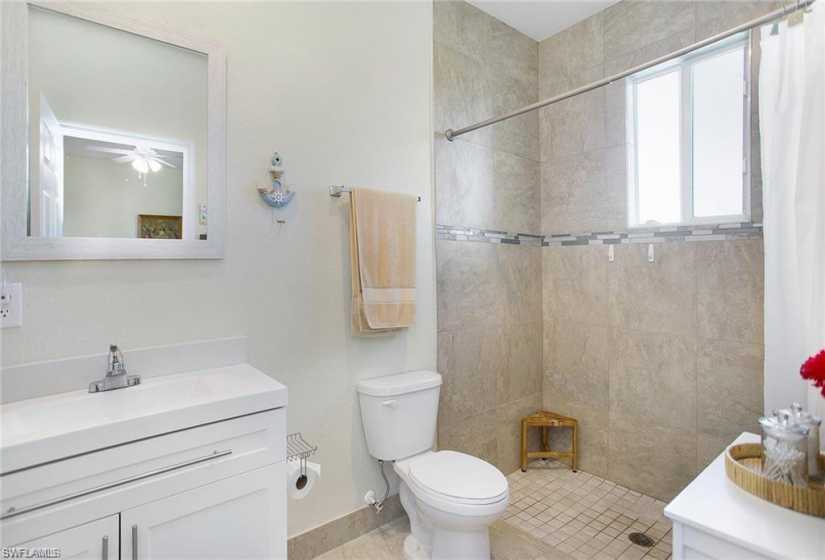 Bathroom with tiled shower, tile flooring, ceiling fan, vanity, and toilet
