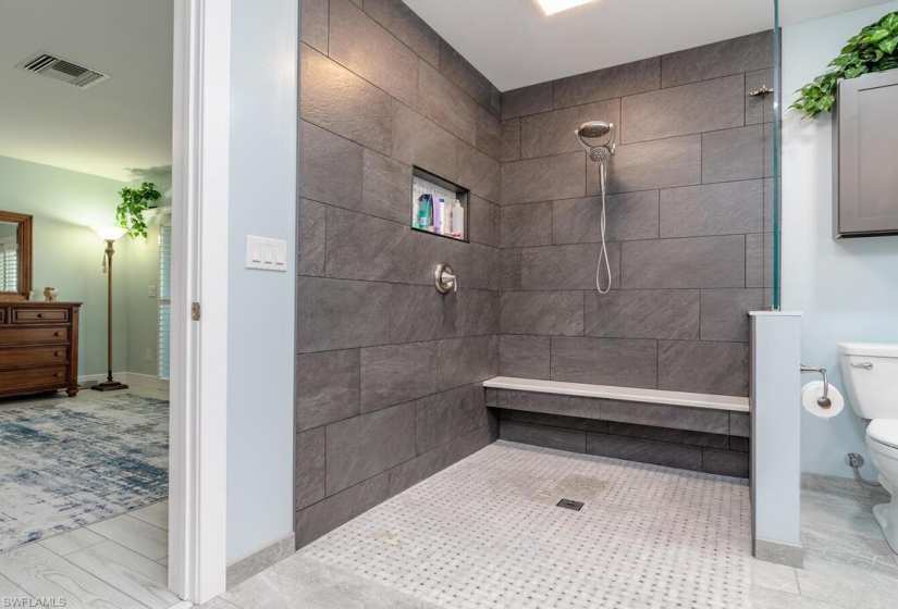 Bathroom featuring a tile shower, vanity, toilet, and tile floors