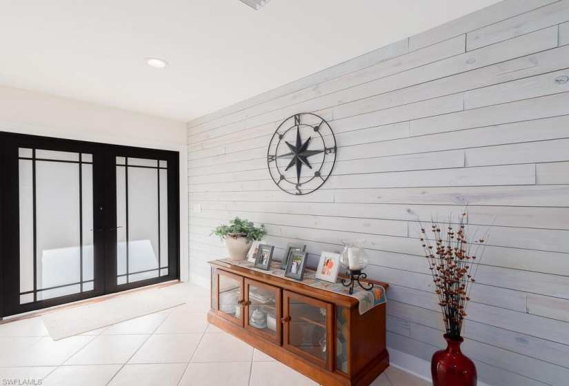 Tiled entryway featuring french doors and wooden walls