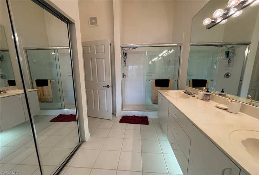 Bathroom with an enclosed shower, oversized vanity, double sink, and tile floors