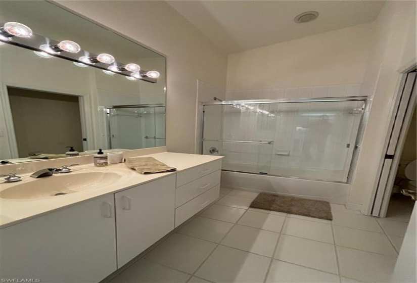 Bathroom with an enclosed shower, tile flooring, and vanity