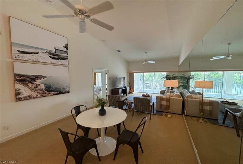 Carpeted dining space featuring high vaulted ceiling and ceiling fan