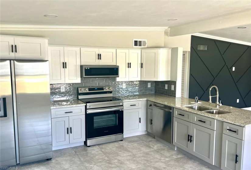 Kitchen with ornamental molding, stainless steel appliances, backsplash, sink, and light tile floors