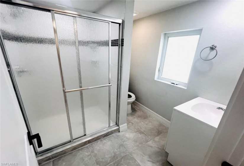 Bathroom featuring tile floors, an enclosed shower, vanity, and toilet