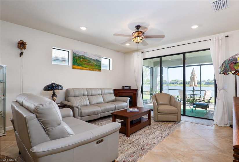 Tiled living room with ceiling fan and a water view