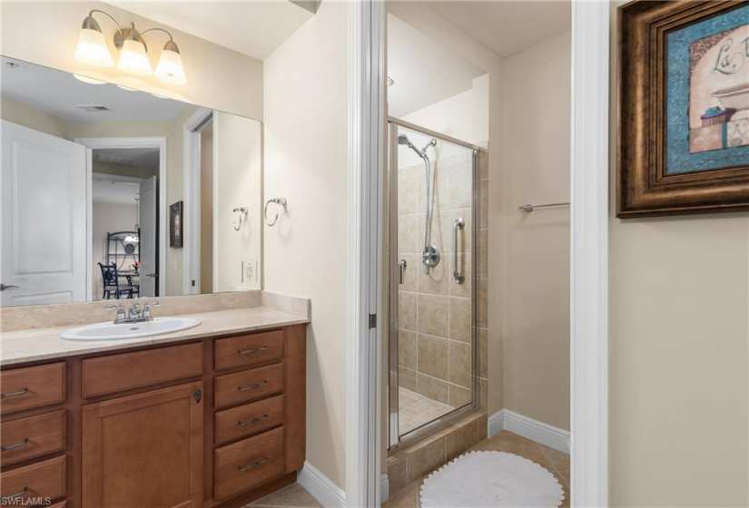 Bathroom with a shower with shower door, tile flooring, and vanity