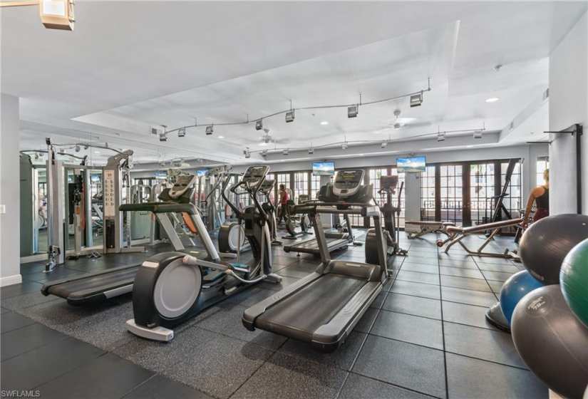 Exercise room featuring tile flooring, french doors, a raised ceiling, and rail lighting