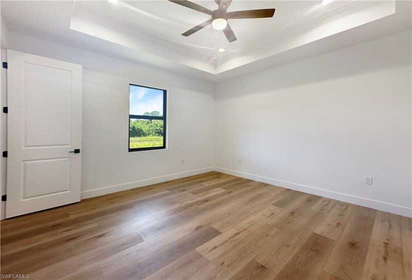 Spare room featuring hardwood / wood-style floors, ceiling fan, a tray ceiling, and ornamental molding