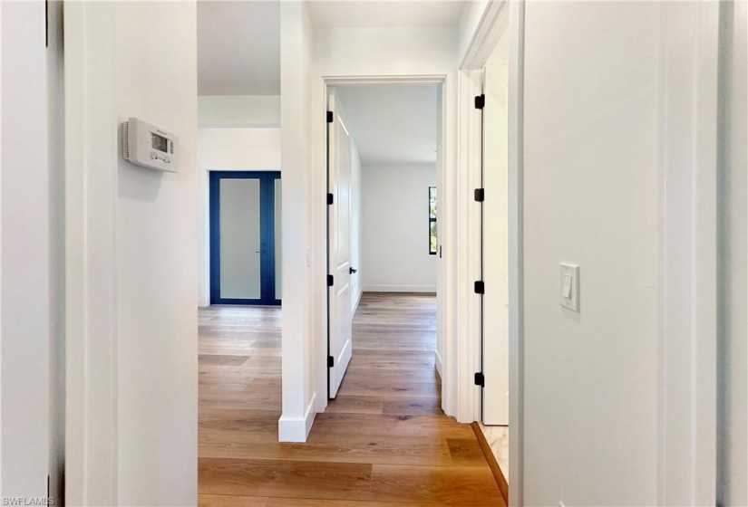 Hall with light hardwood / wood-style flooring between guest bedrooms