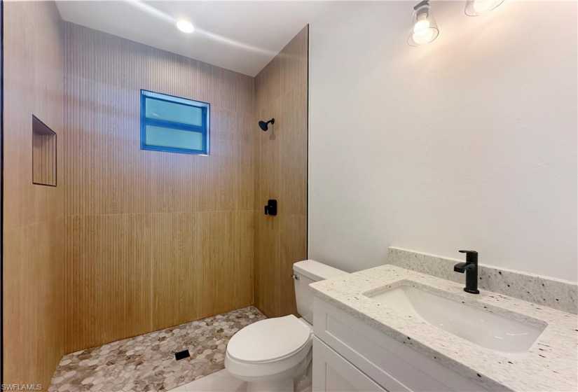 Guest Bathroom with tiled shower, vanity, and toilet