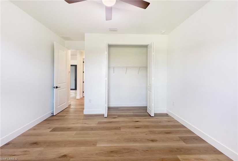 Unfurnished bedroom featuring hardwood / wood-style flooring, a closet, and ceiling fan