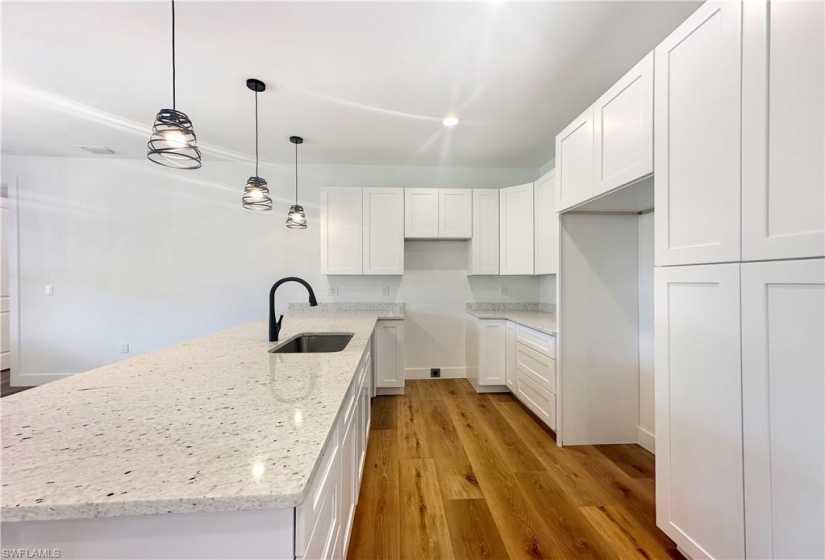 Kitchen with light granite counters, sink, white cabinetry, and light hardwood / wood-style flooring
