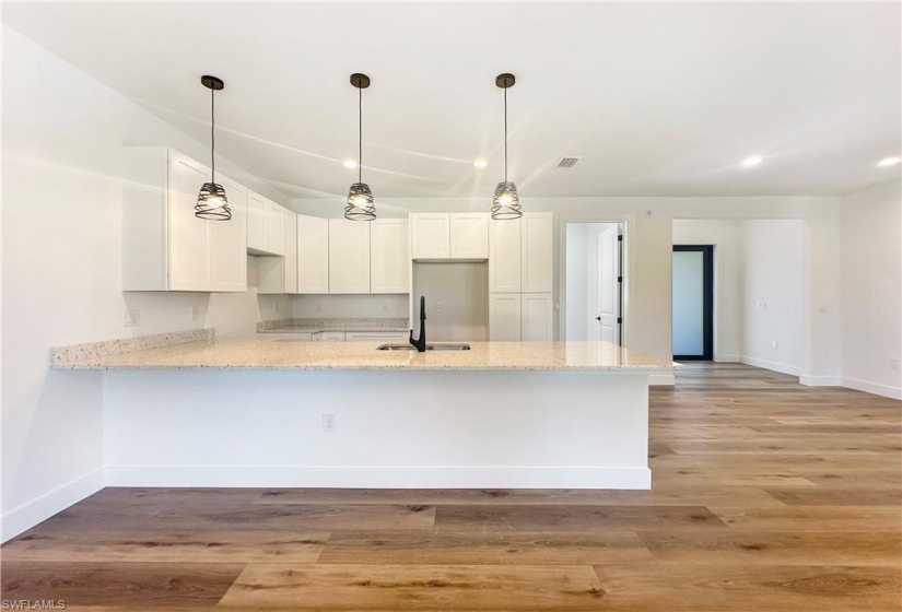 Kitchen featuring light stone countertops, sink, light hardwood / wood-style floors, and white cabinets