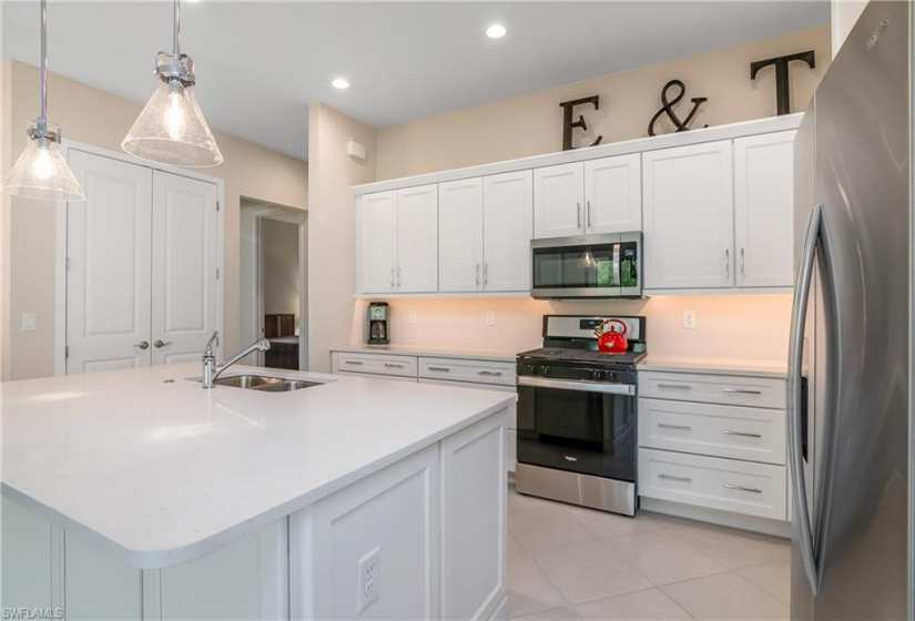 Kitchen with appliances with stainless steel finishes, white cabinetry, sink, and a kitchen island with sink