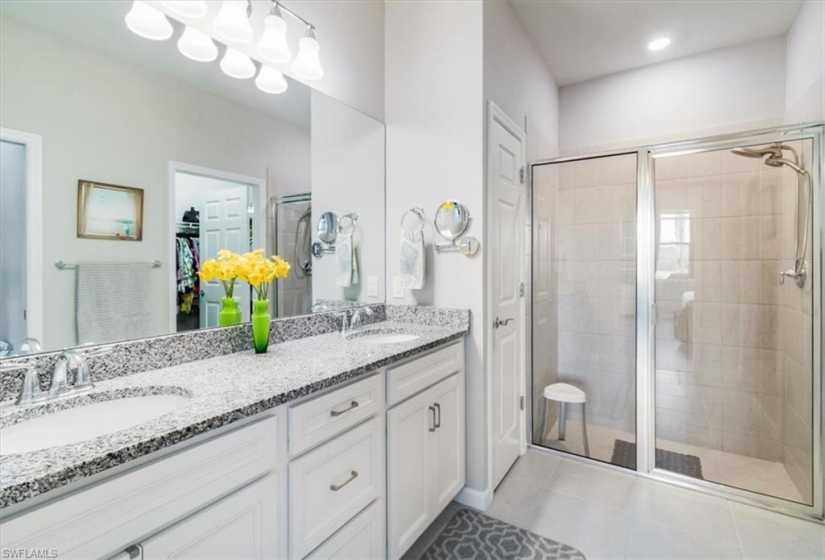 Bathroom with tile flooring, a shower with shower door, and double vanity