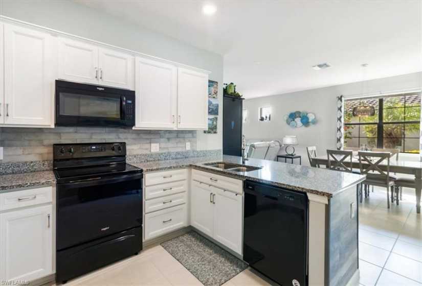 Kitchen featuring black appliances, sink, kitchen peninsula, and light tile floors