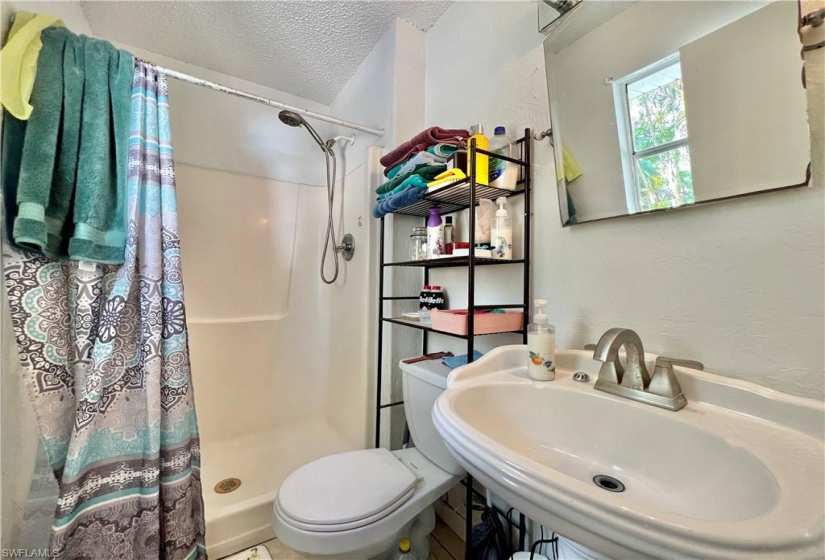 Bathroom with a shower with curtain, sink, a textured ceiling, and toilet