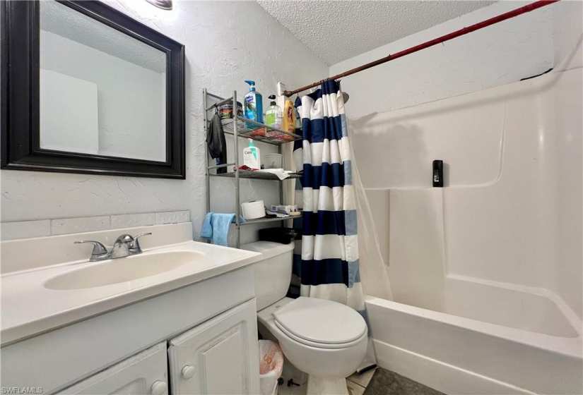Full bathroom featuring a textured ceiling, shower / tub combo, tile floors, large vanity, and toilet