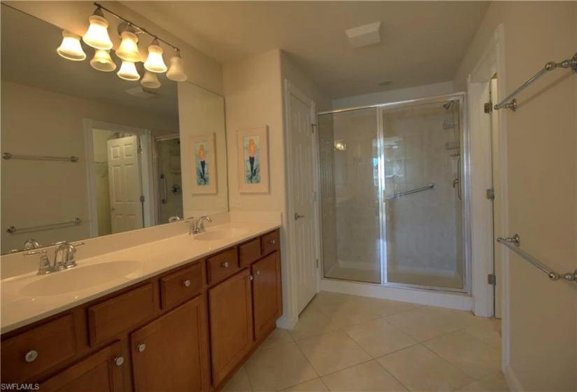 master bathroom with walk in shower, dual sinks, and walk in closet