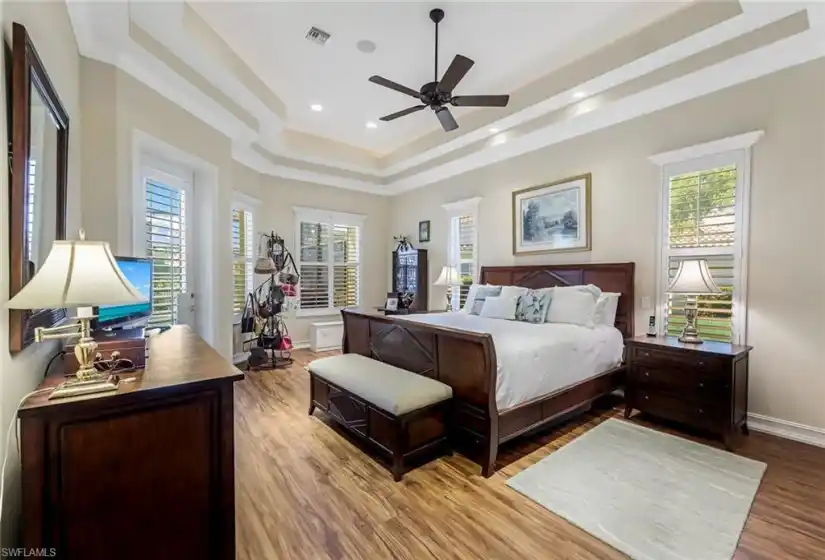 Lovely primary bedroom with double tray ceiling detail, recessed lights, plantation shutters, and direct access to your backyard oasis!