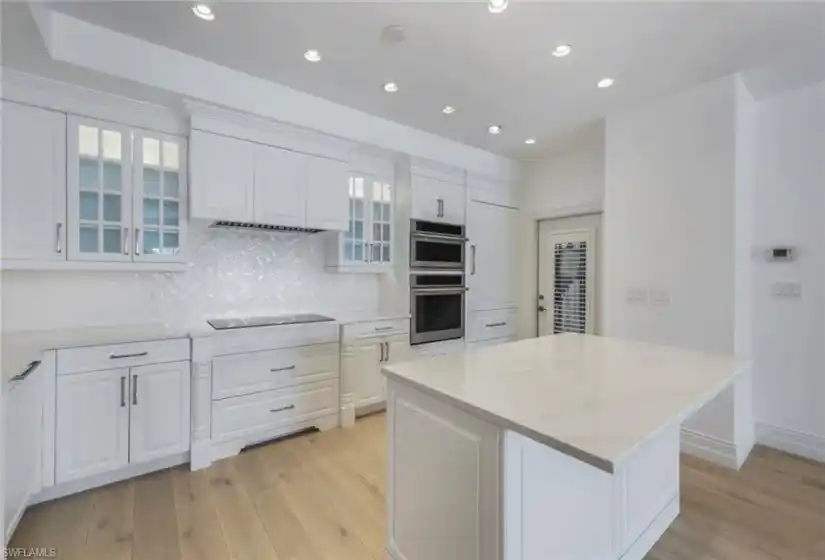 Kitchen white wood cabinetry, stainless steel appliances, quartz countertops and tile backsplash.