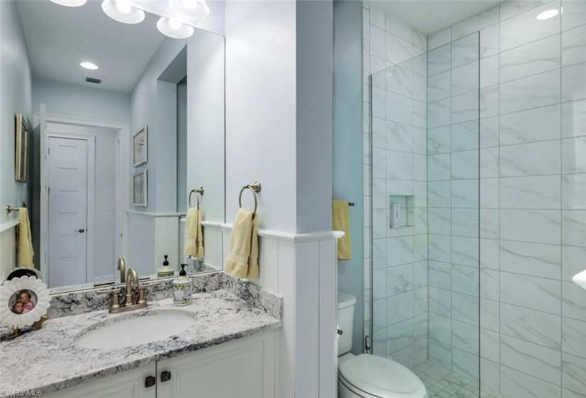 Guest bath has been updated with shiplap walls and features a walk-in frameless shower.