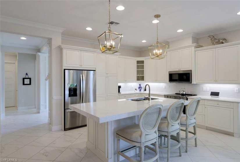 Beautiful white kitchen cabinets with crown molding, stainless steel appliances and quartz countertops.