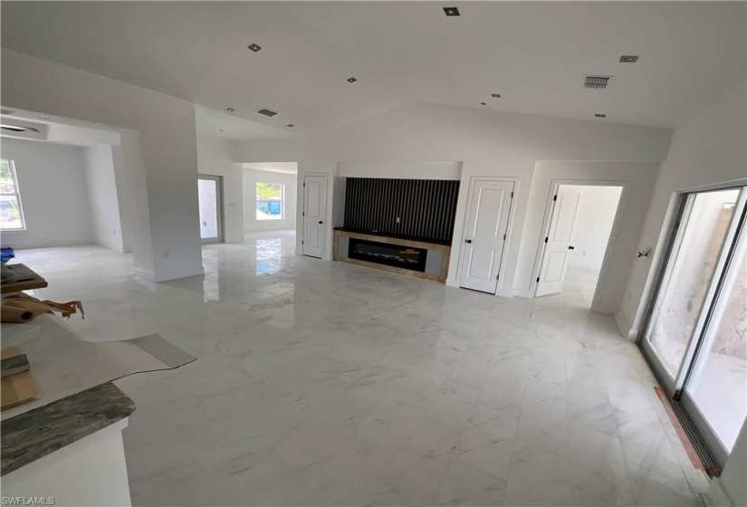 Unfurnished living room featuring vaulted ceiling and light tile floors